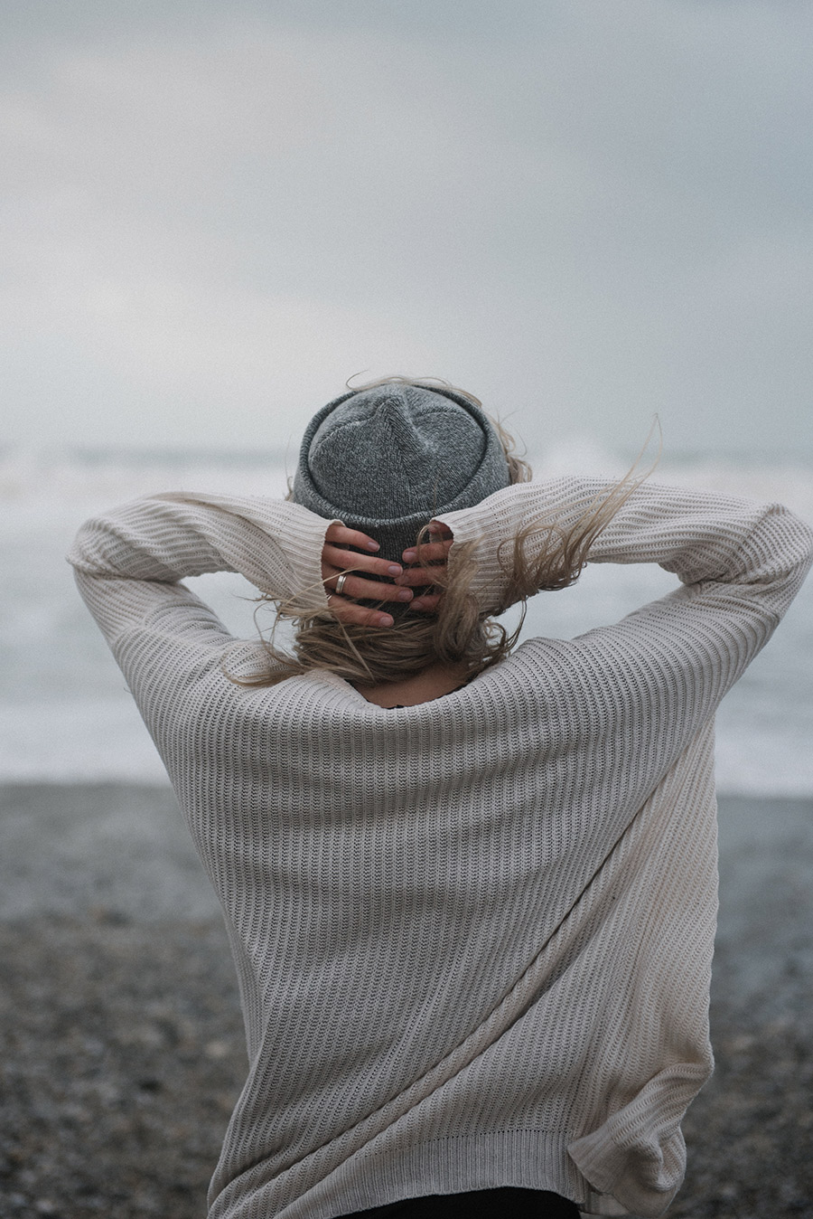 junge blonde Frau mit Hut Strand windiges Wetter