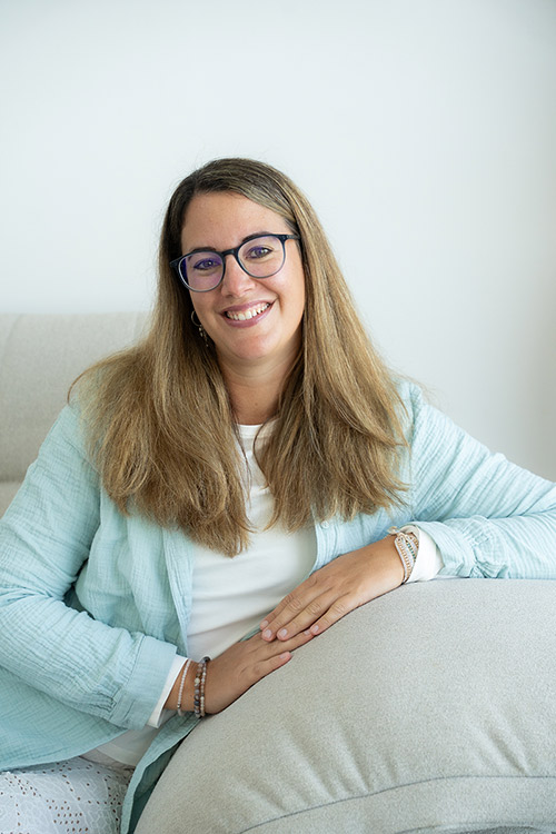 Melanie sitzt auf einer Couch und schaut dich an