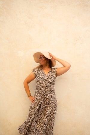 Frau vor Wand greift an Hut