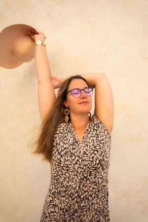 Frau vor Wand greift an Hut