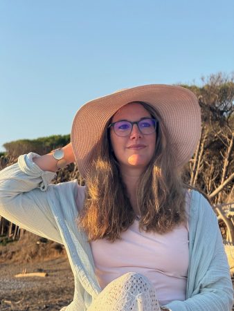 Melanie mit Hut am Strand und sieht in die ferne
